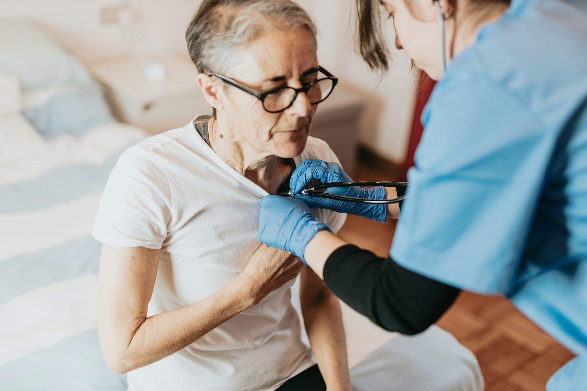 a woman wearing blue gloves and holding a stethoscope