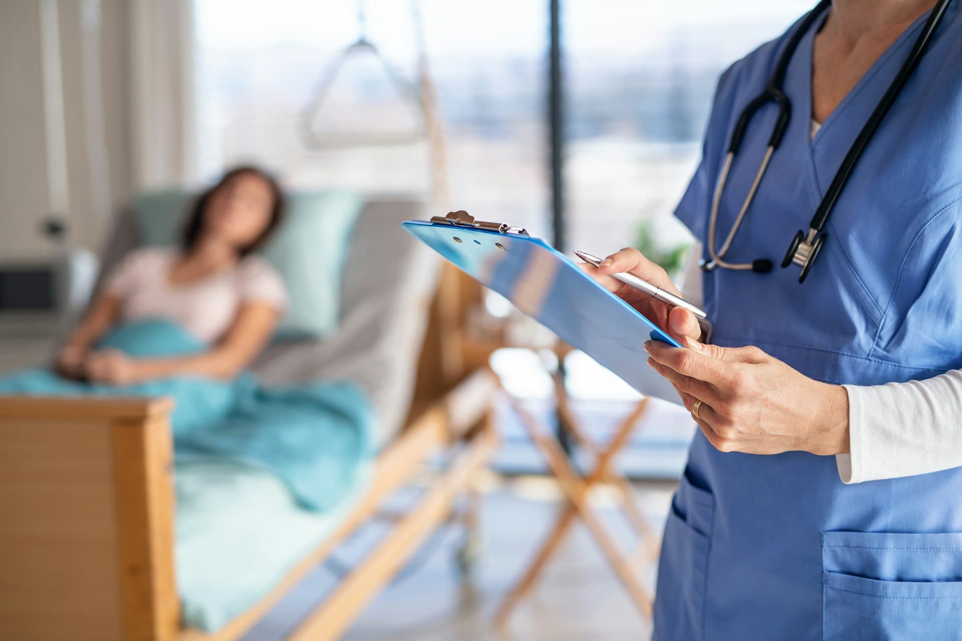 a doctor holding a clipboard in front of a woman lying in bed