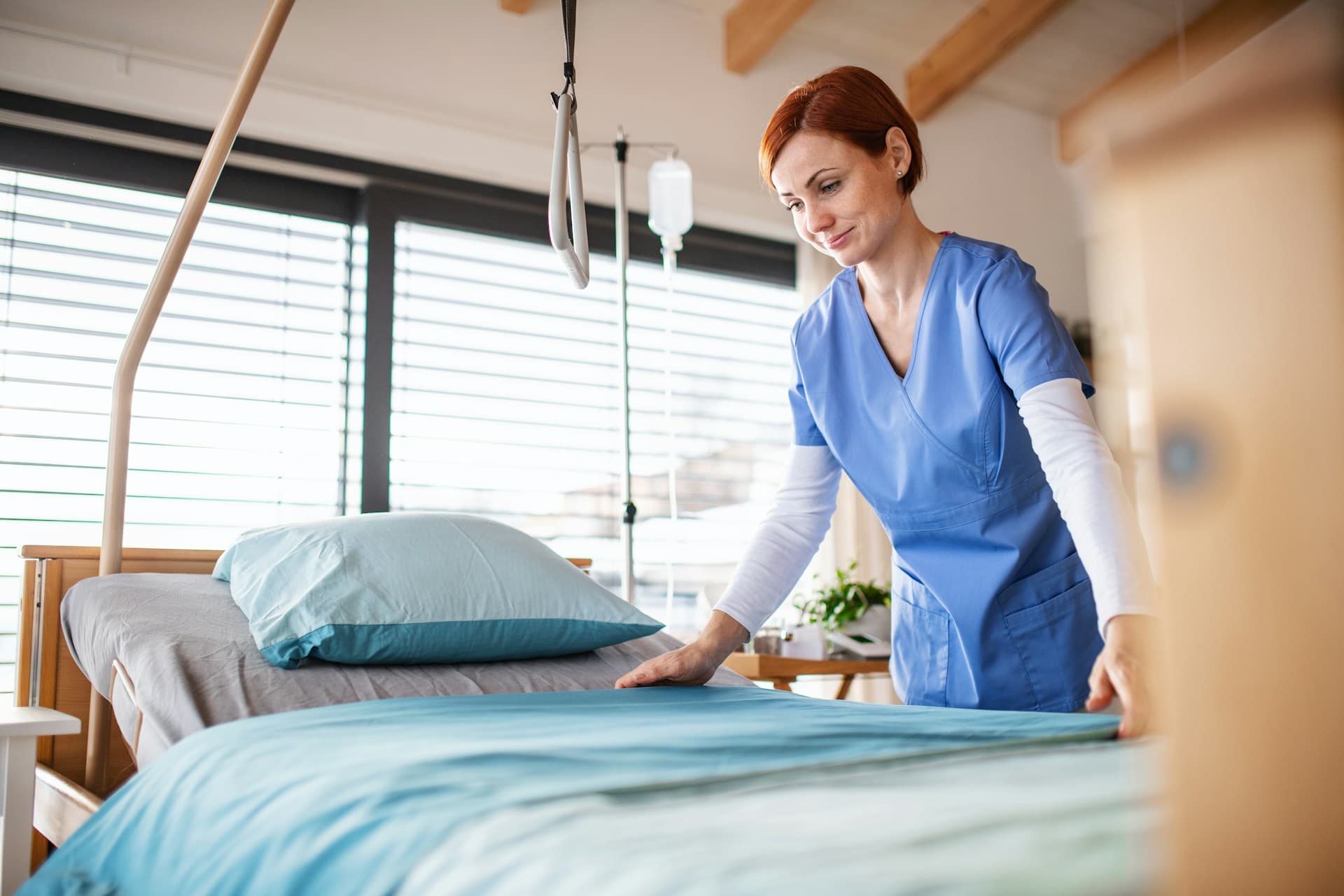 a woman in a blue scrubs folding a bed