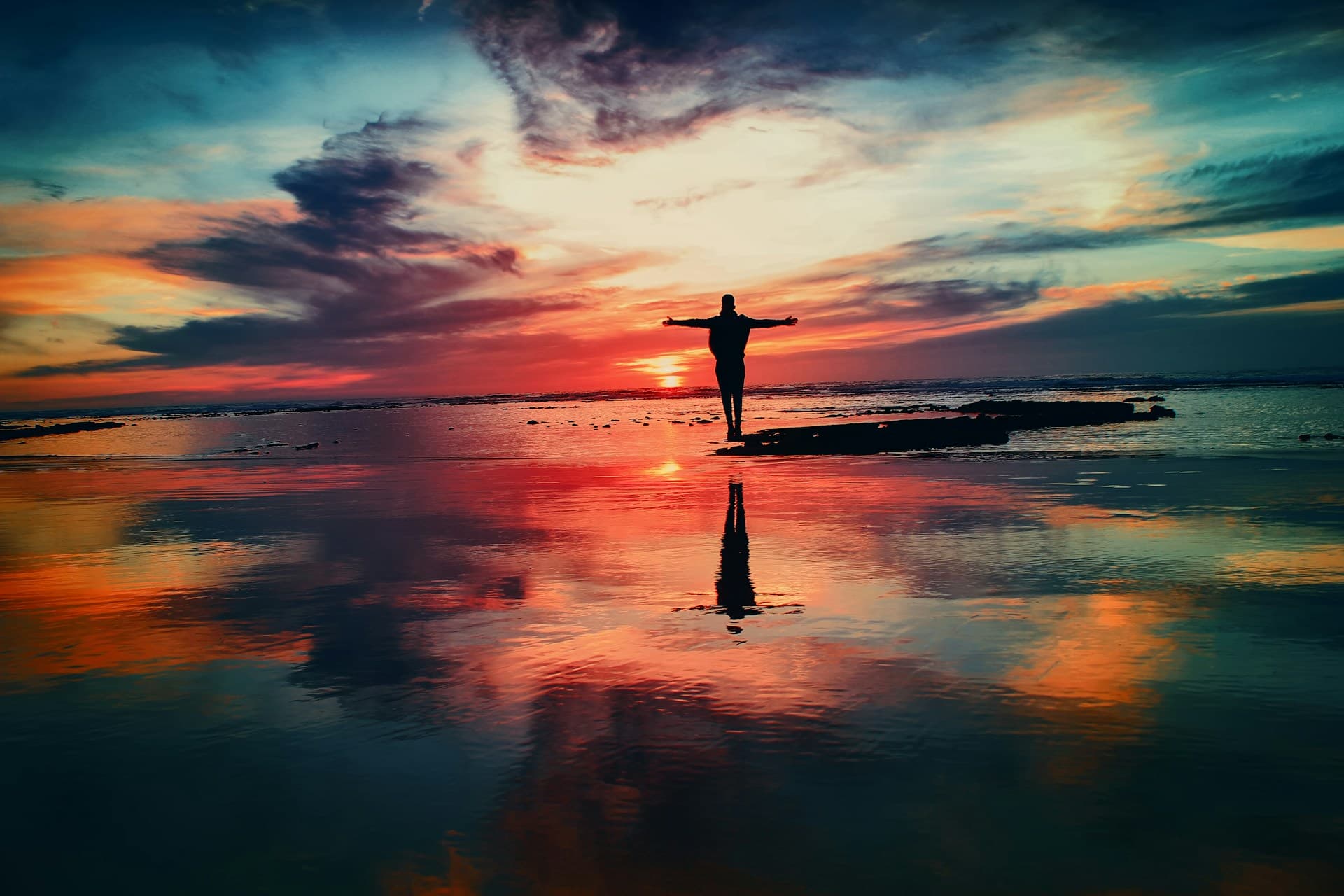 a person standing on a beach with their arms outstretched